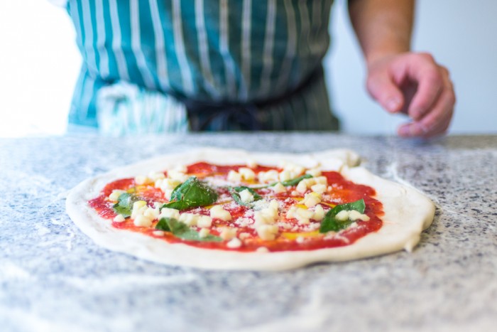 Man making pizza dough on a stone counter
