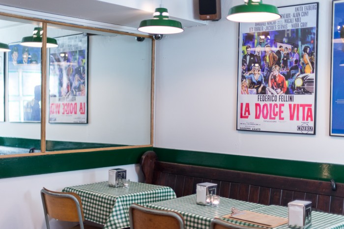Restaurant decor with green table cloths and old Italian movie prints
