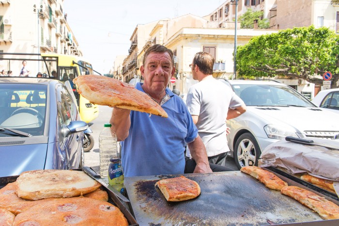 Man selling Sfincione pizza at a street food market in Palermo Sicily. Man selling Sfincione pizza at a street food market in Palermo Sicily.