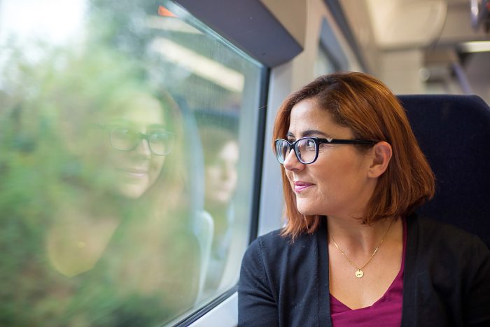 Young woman on a train looking out of the window at the landscape in England
