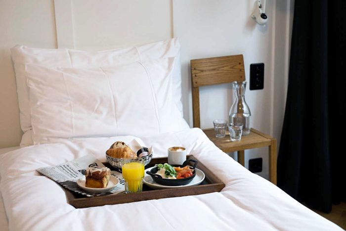 Breakfast served on a wooden tray on a bed in a hotel room Breakfast served on a wooden tray on a bed at Marktgasse Hotel in Zurich