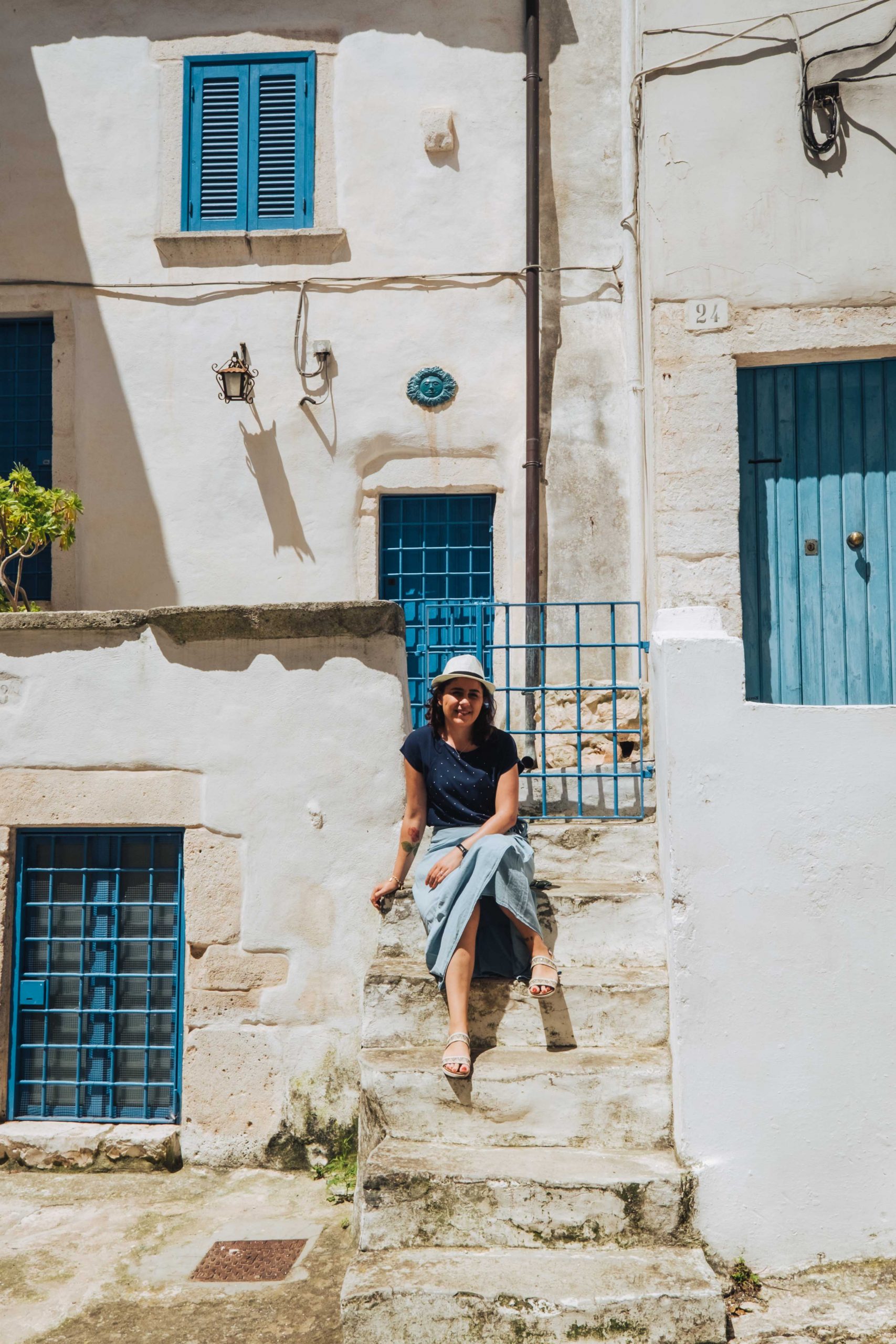 Young woman sitting on old steps of a white building in Ostuni, Puglia Young woman sitting on old steps of a white building in Ostuni, Puglia