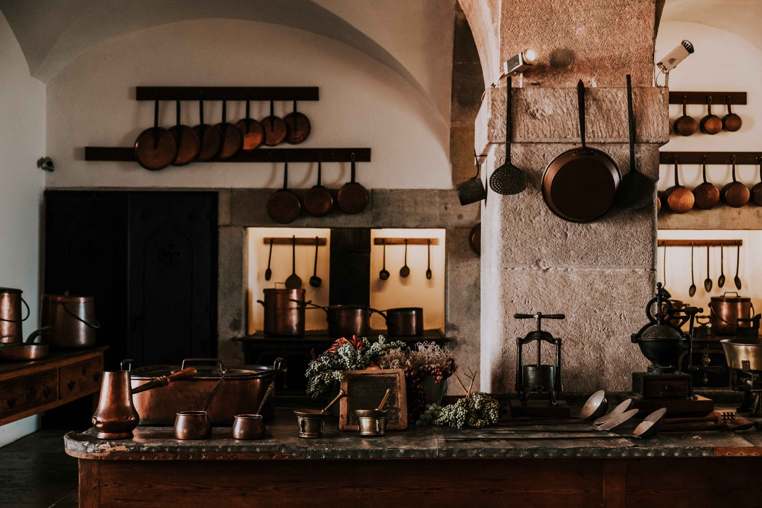 Old style, rustic kitchen design with stone walls and copper pans