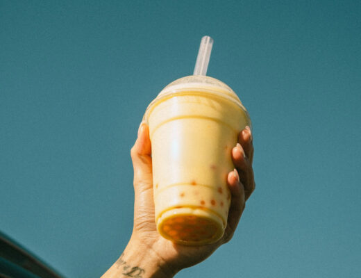 A hand holding a cup with bubble tea