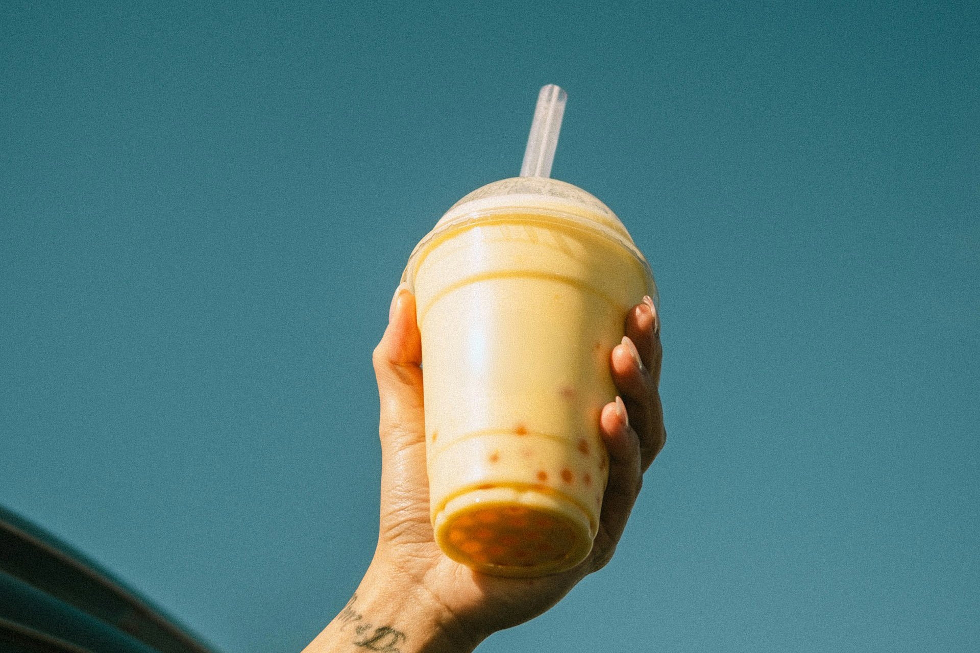 A hand holding a cup with bubble tea