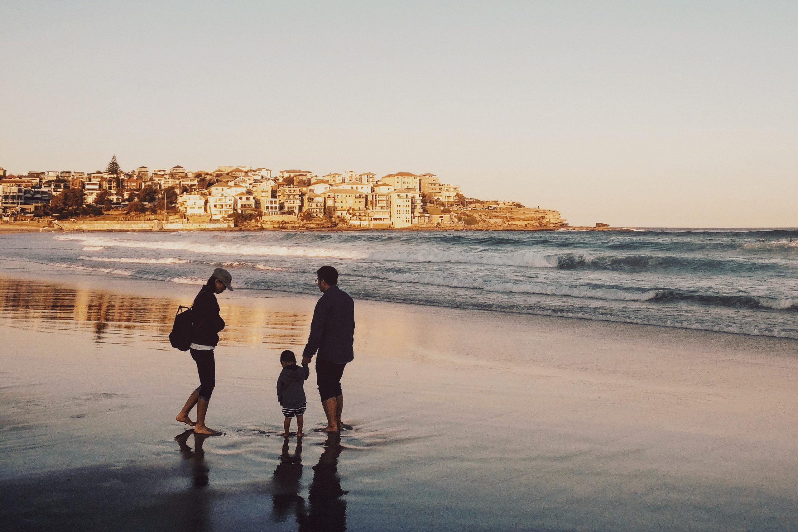 Family with kid walking on beach in the evening