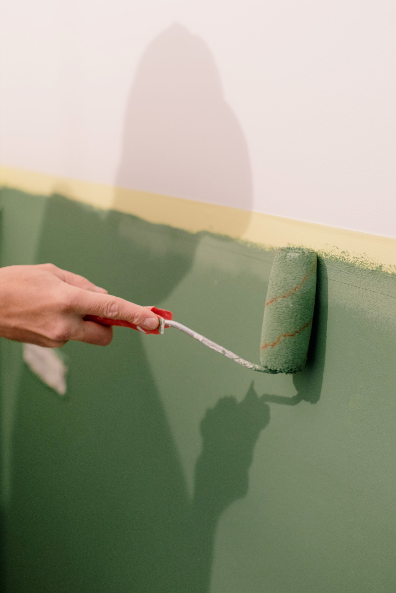 Person painting house walls in green