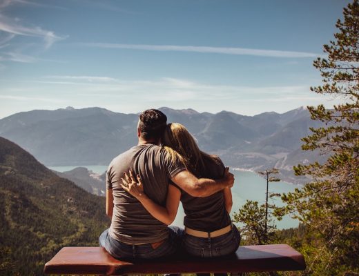 Man and woman in love, sitting on a bench in the mountains