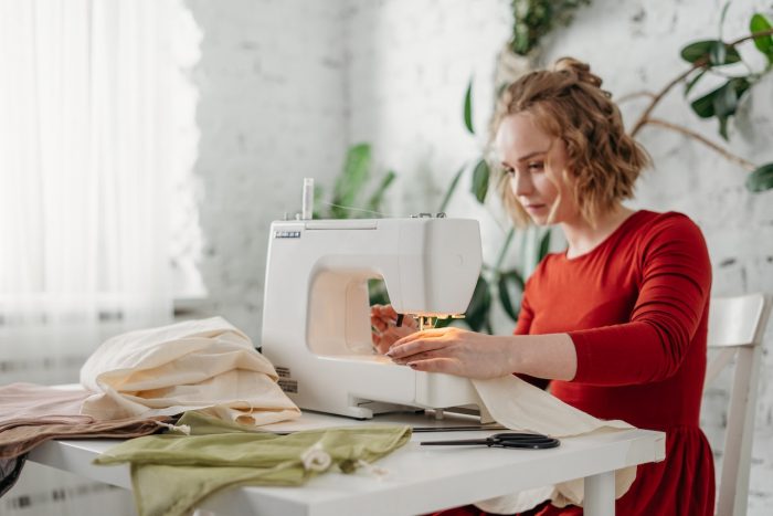 Woman sewing with a machine while sitting on a chair Woman sewing with a machine while sitting on a chair