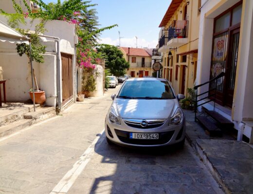 a grey car parked in front of a concrete building in a small town in Greece