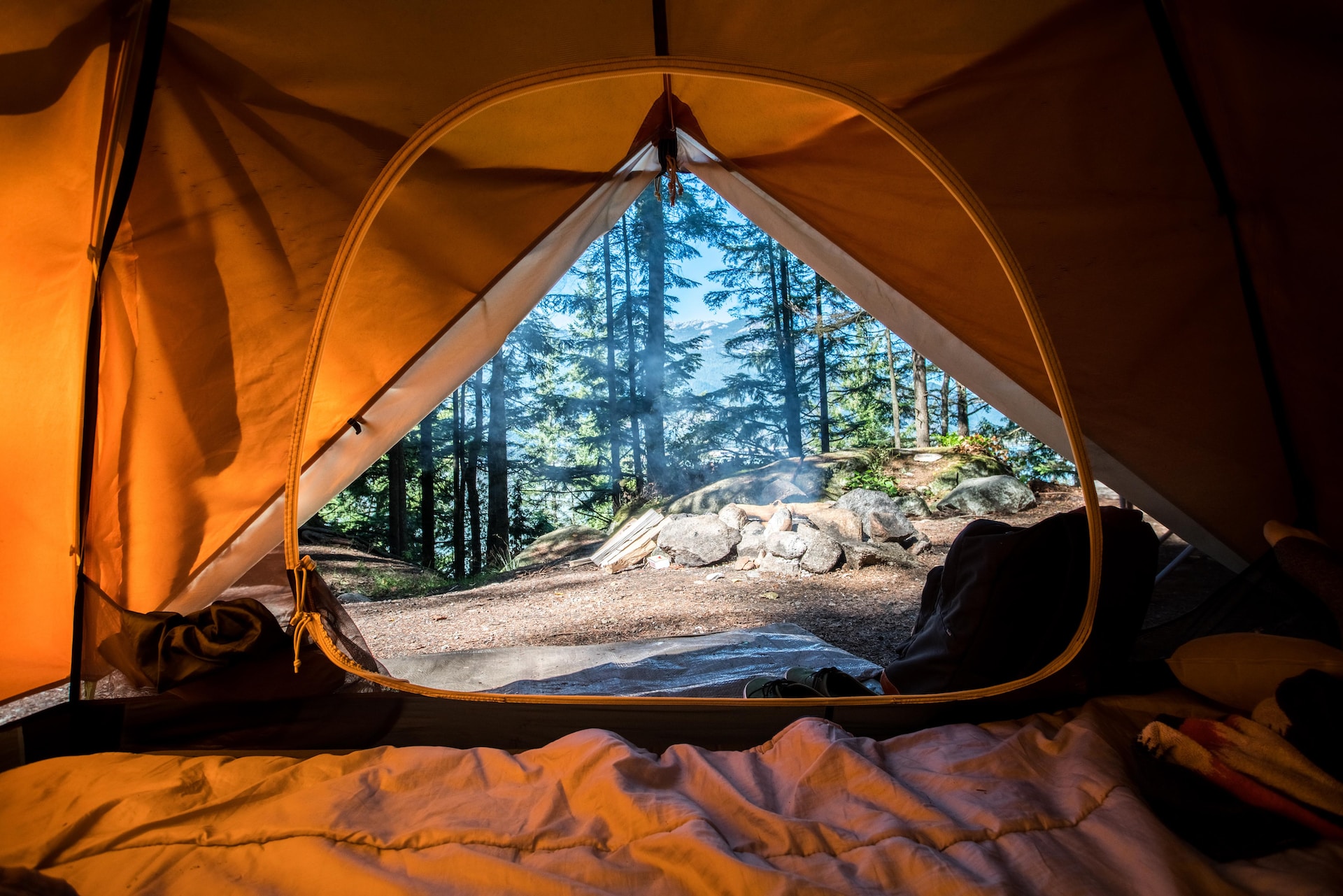 orange camping tent overlooking mountain and green trees