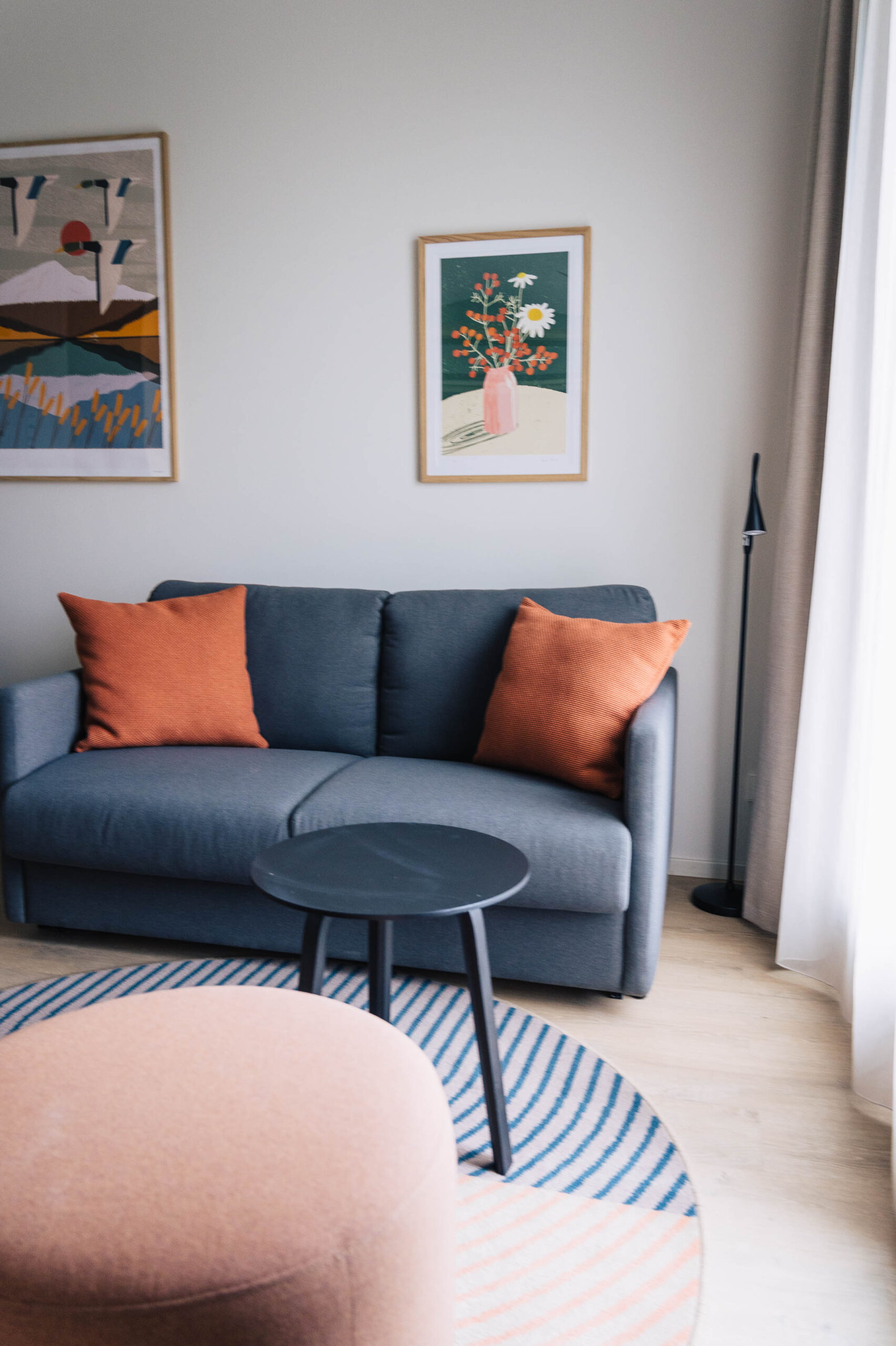 Living room lounge with blue sofa, orange cushions and wooden floor Living room lounge with blue sofa, orange cushions and wooden floor