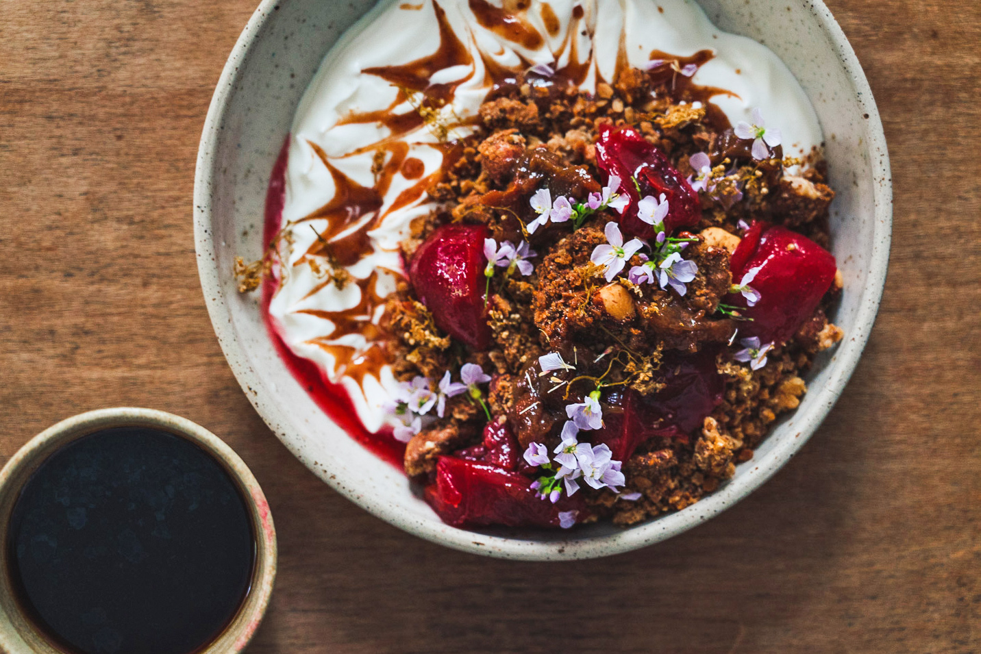 Yoghurt and granola and fruit bowl for breakfast with a cup of black coffee