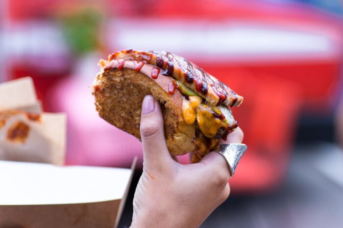 A woman holding a hot dog at a street food festival