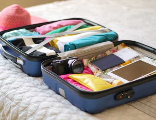 clothes and assorted travel things in a trolley suitcase on a bed