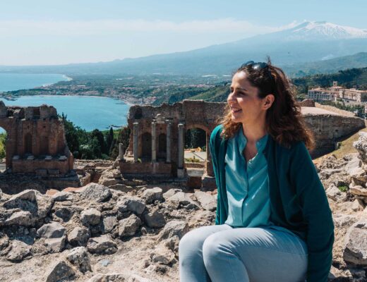 Young woman sitting in front of the Greek amphitheatre in Taormina, Sicily