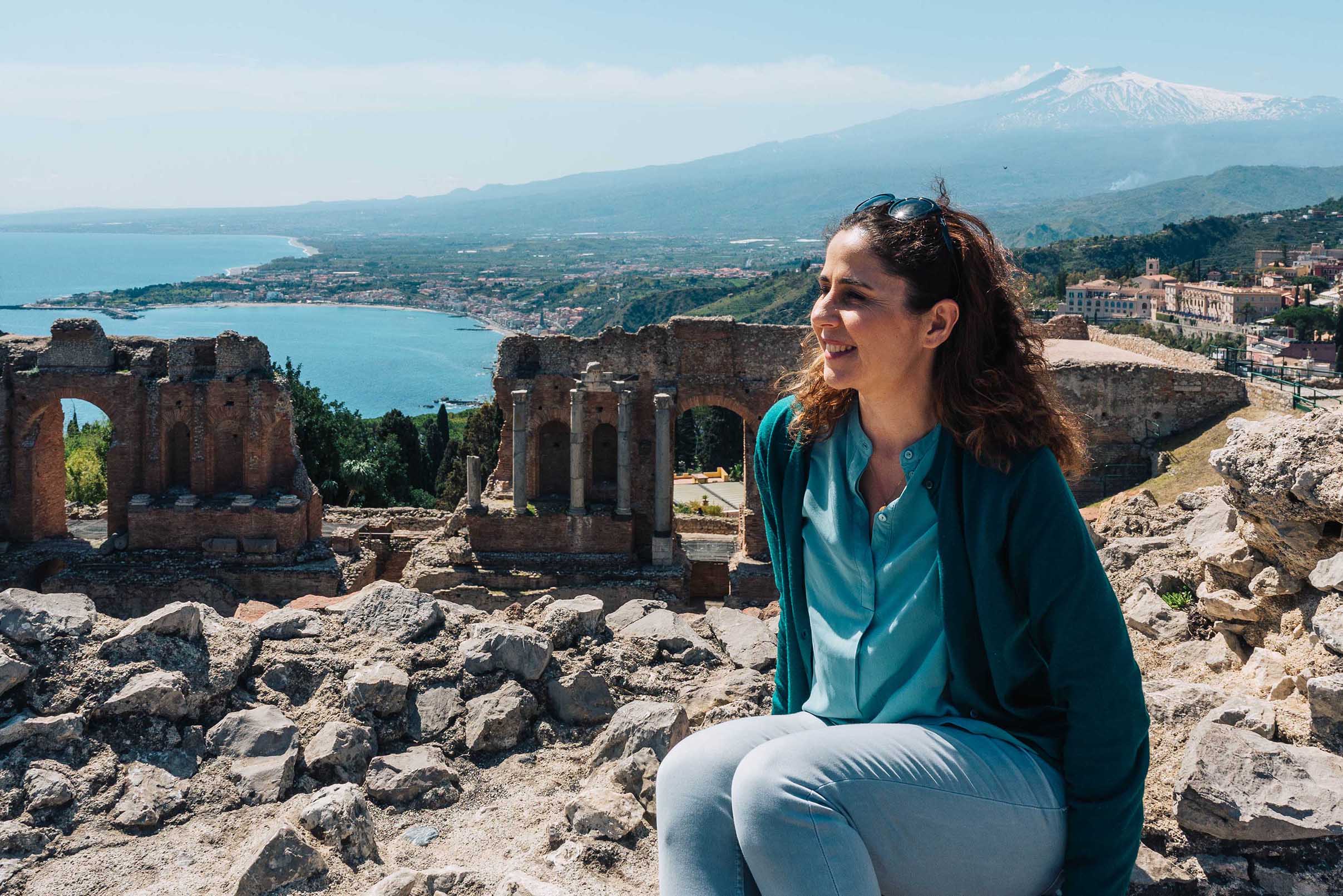Young woman sitting in front of the Greek amphitheatre in Taormina, Sicily