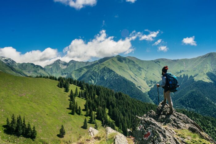 A man hiking and standing on a rock looking at mountains in Romania A man hiking and standing on a rock looking at mountains in Romania