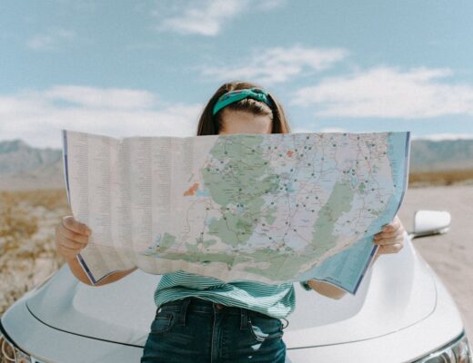 woman standing in front of a car looking at a road map