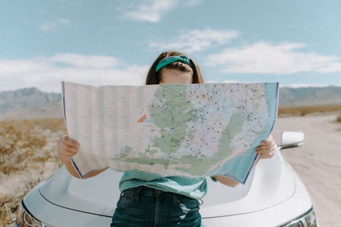 woman standing in front of a car looking at a road map