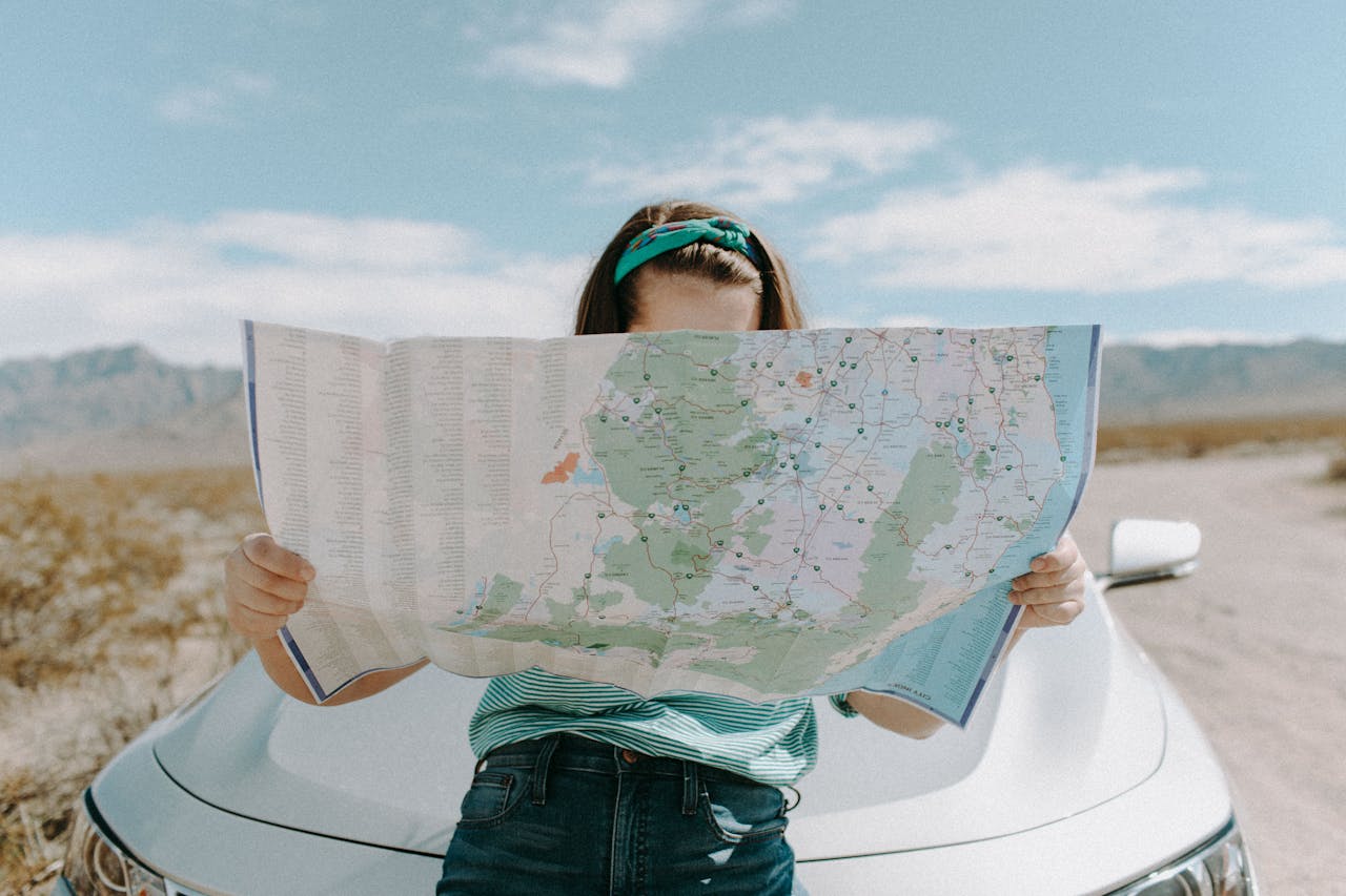 woman standing in front of a car looking at a road map