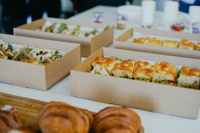 a table topped with food boxes containing sandwiches and pastries