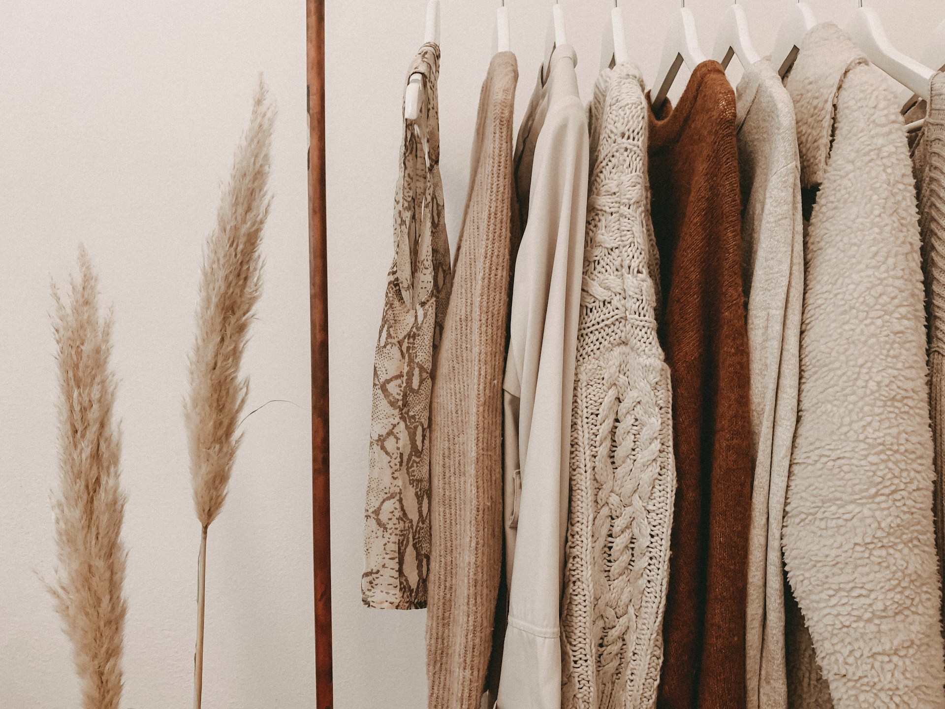 White and beige clothes hanging in a wardrobe