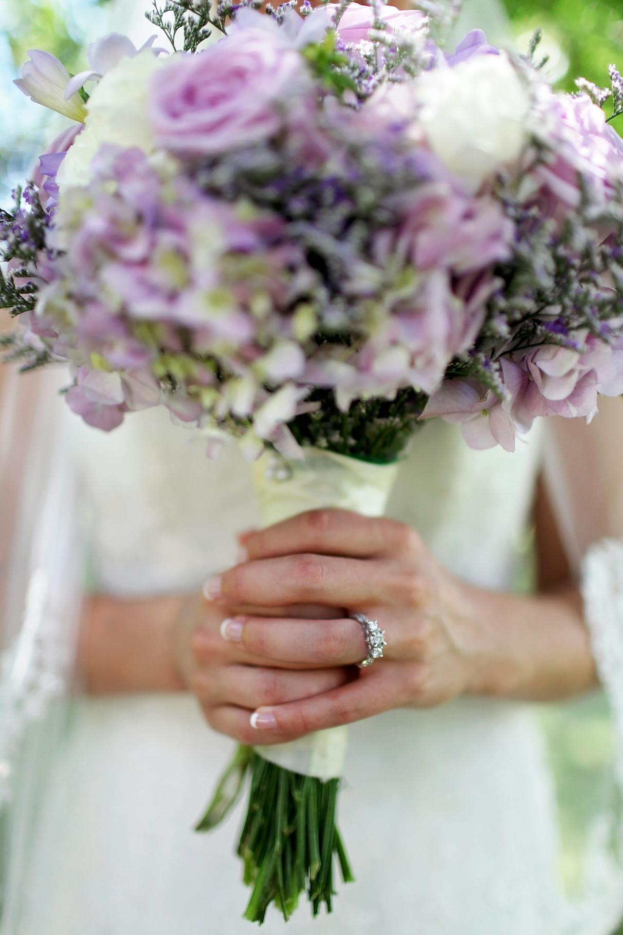 A bride holding a bouquet of flowers with an engagement ring on her left hand