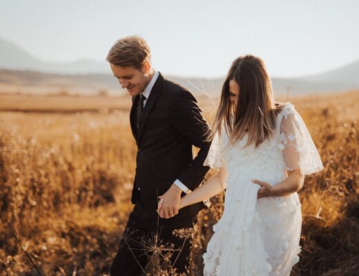 Bride wearing a white wedding dress and groom in a field
