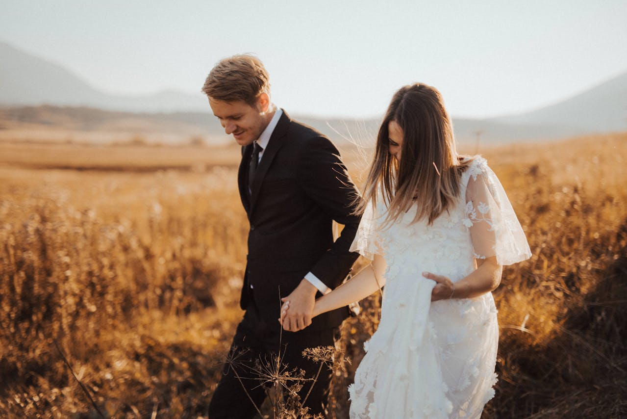 Bride wearing a white wedding dress and groom in a field