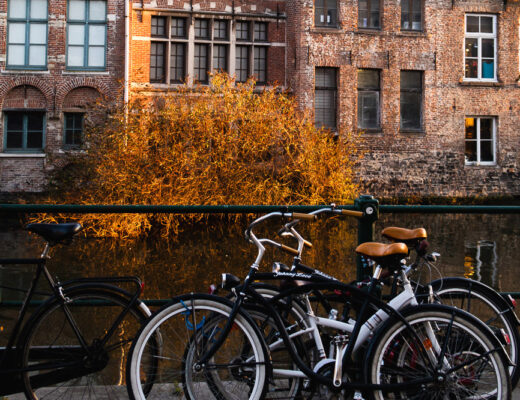 bicycle parked by the river in front of old buildings in Ghent