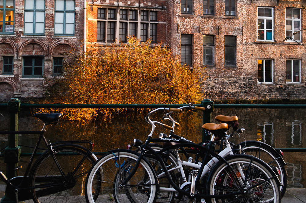 bicycle parked by the river in front of old buildings in Ghent