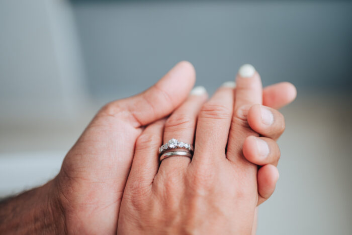 man and woman holding hands with a white gold engagement ring with diamonds and a wedding band