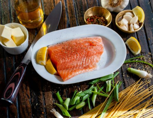 a table with salmon fillet on a plate with lemon and butter