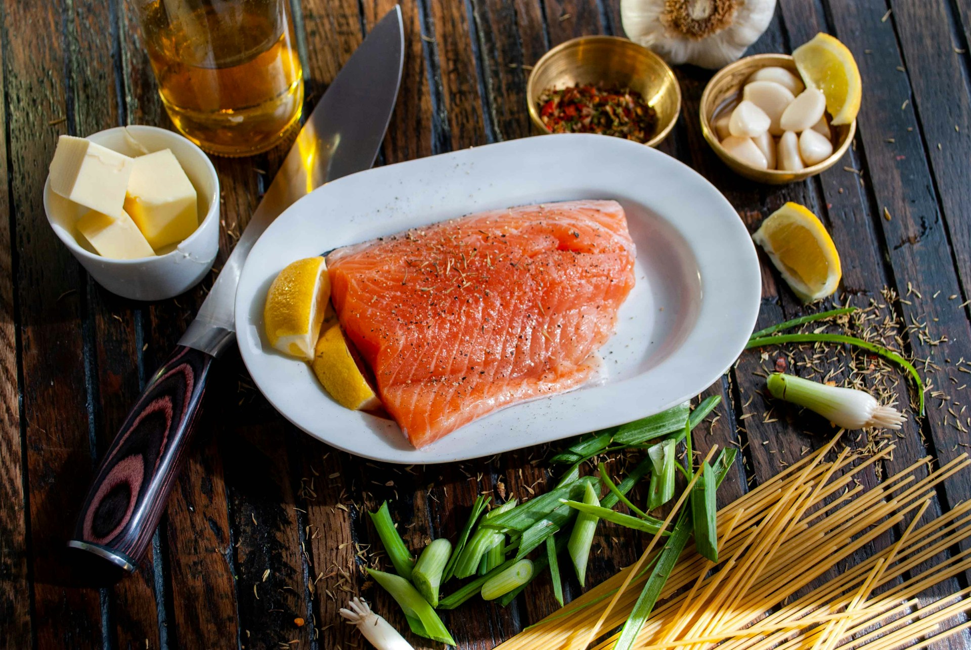 a table with salmon fillet on a plate with lemon and butter