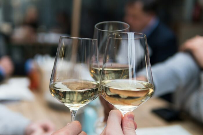 hands holding three white wine glasses hands holding three white wine glasses