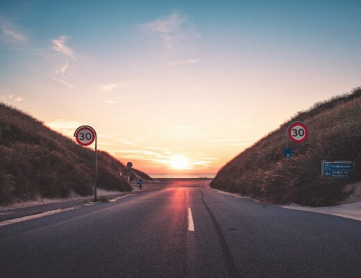 grey asphalt, road in Denmark going into the sea at sunset