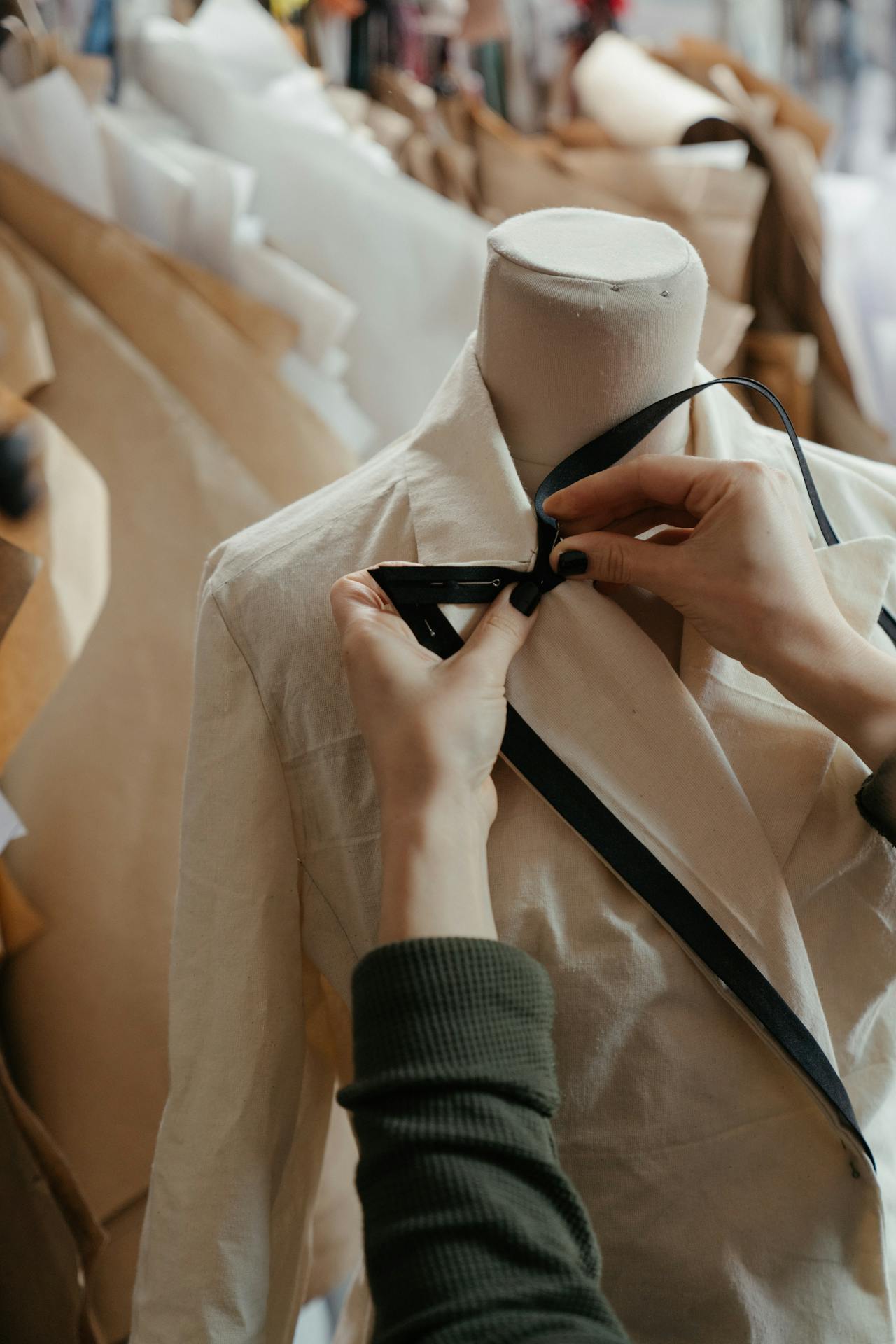 tailor stitching a white suit blazer on a mannequin