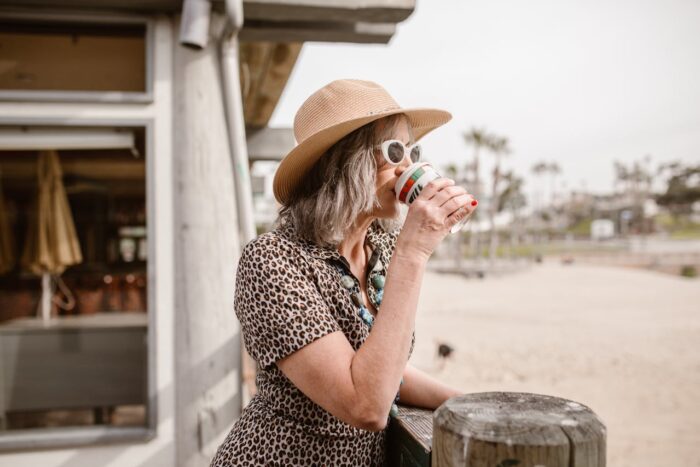 Blonde woman drinking takeaway coffee by the beach in San Diego Blonde woman drinking takeaway coffee by the beach in San Diego
