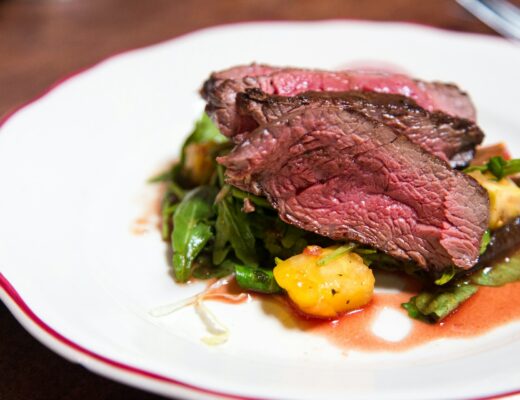 medium rare sliced steak on a white ceramic plate with potatoes