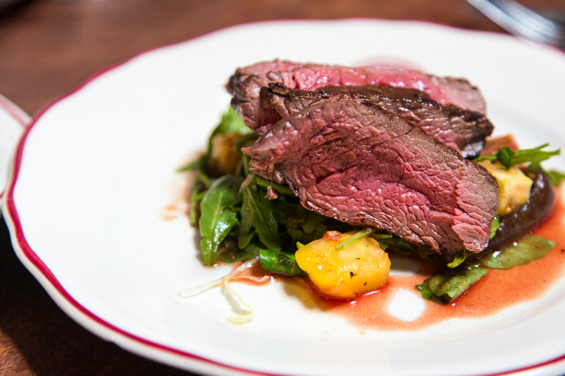 medium rare sliced steak on a white ceramic plate with potatoes