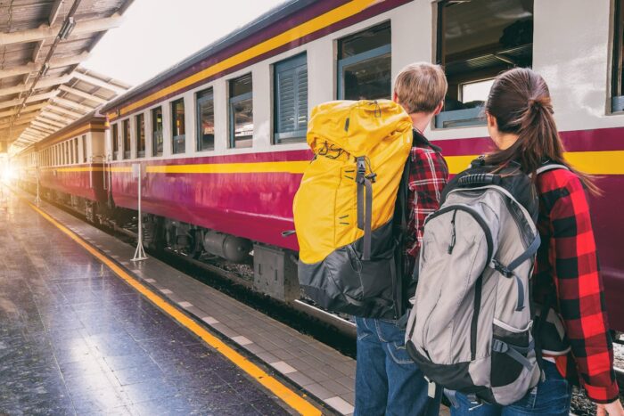 young people with backpacks at the train station waiting for train young people with backpacks at the train station waiting for train