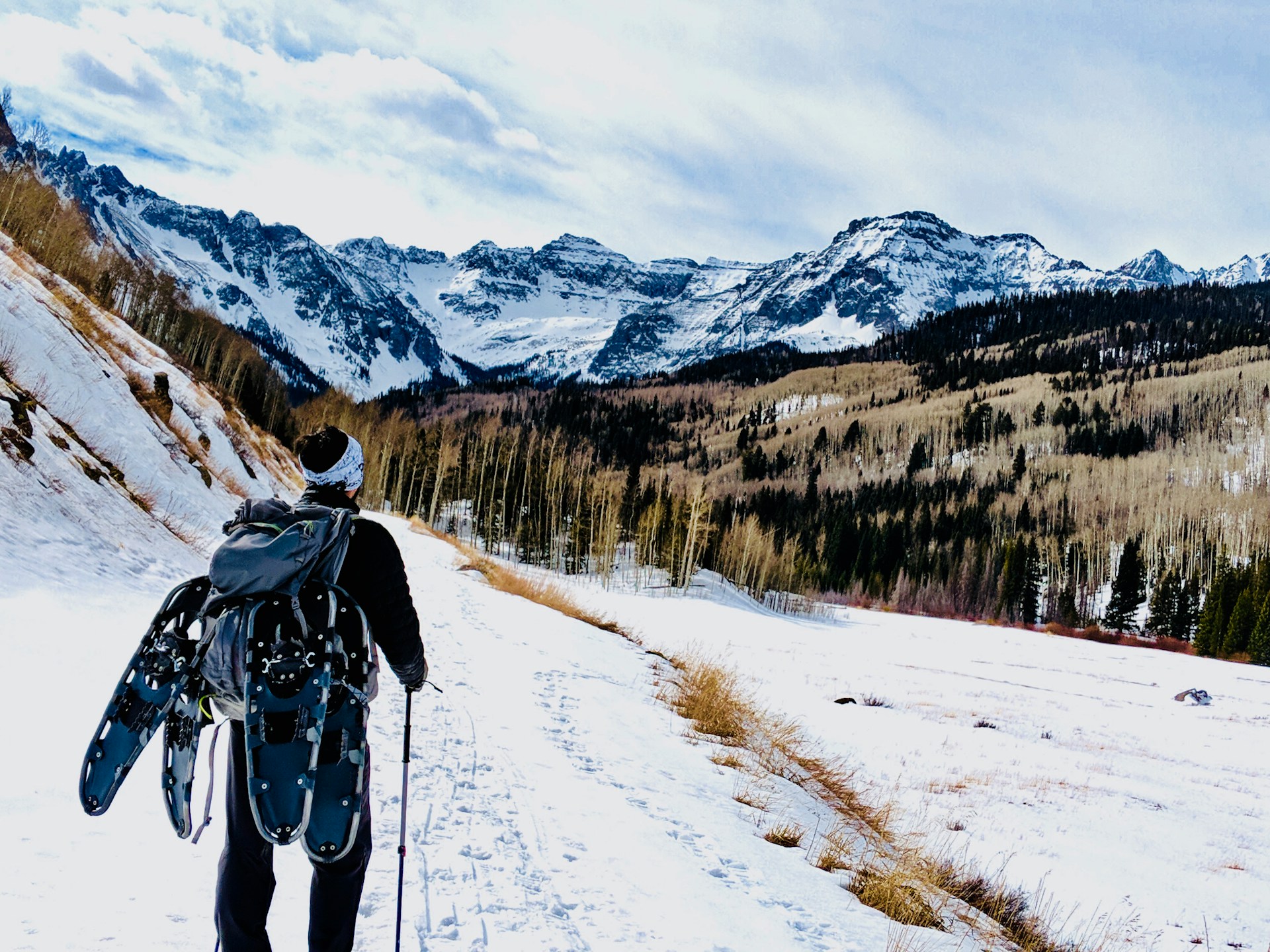 man wearing backpack climbing mountain with snow