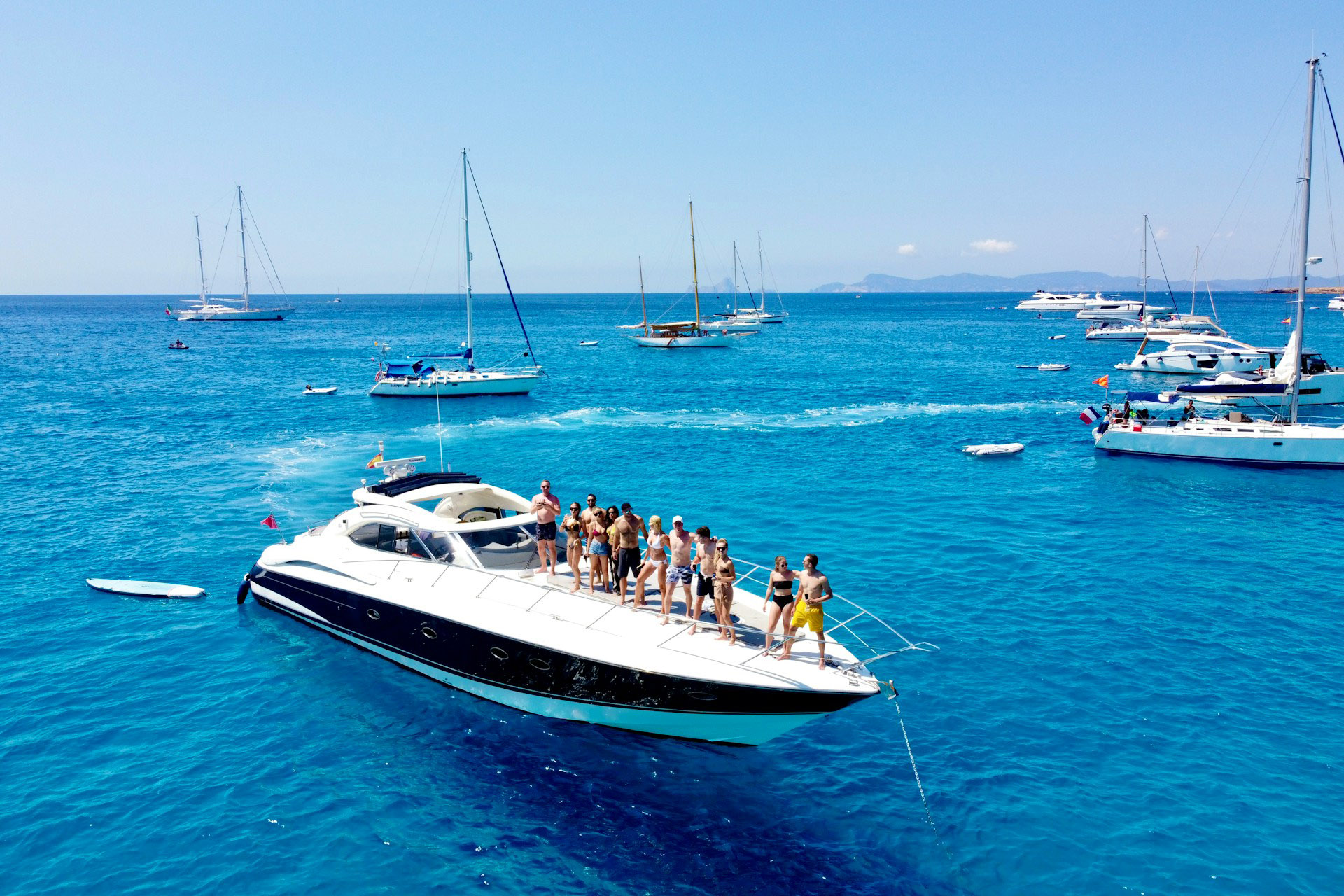 A group of friends enjoying a private event on the deck of a luxury white yacht in turquoise waters, showcasing the exclusivity of boat-based celebrations.