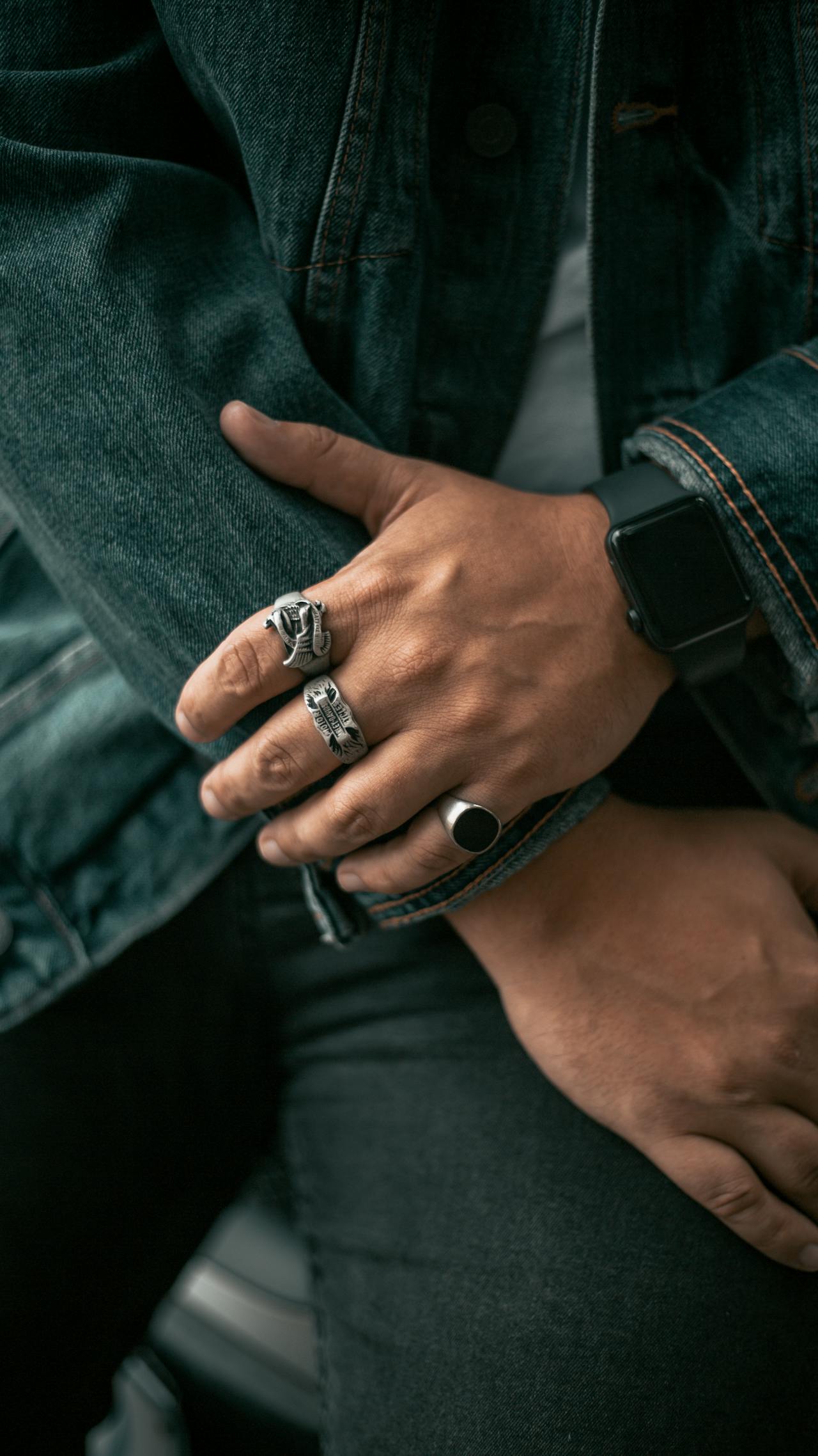 close up photo of a man's hand with silver rings and men's signet ring