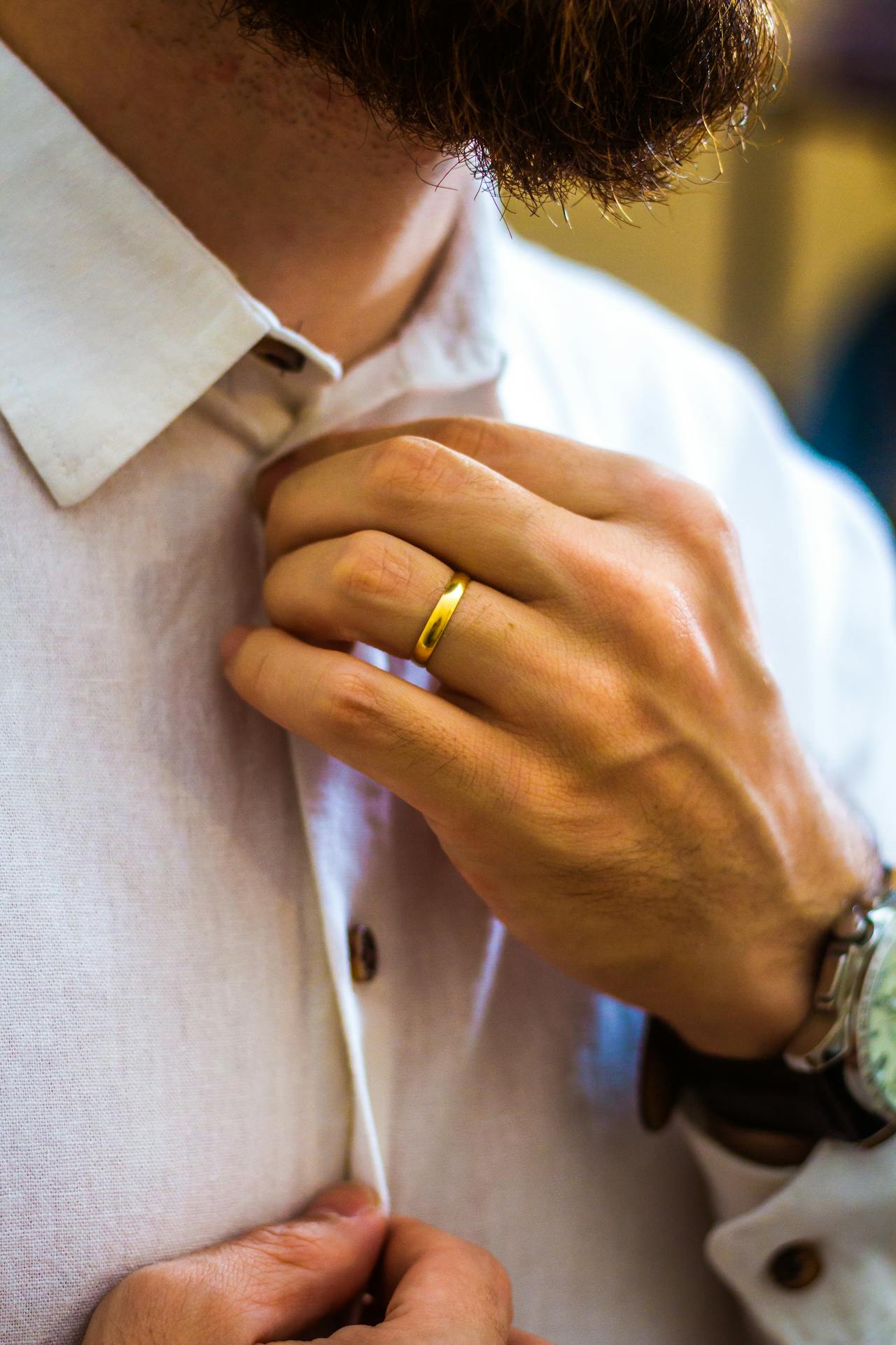 man hand with brushed gold wedding band on white shirt