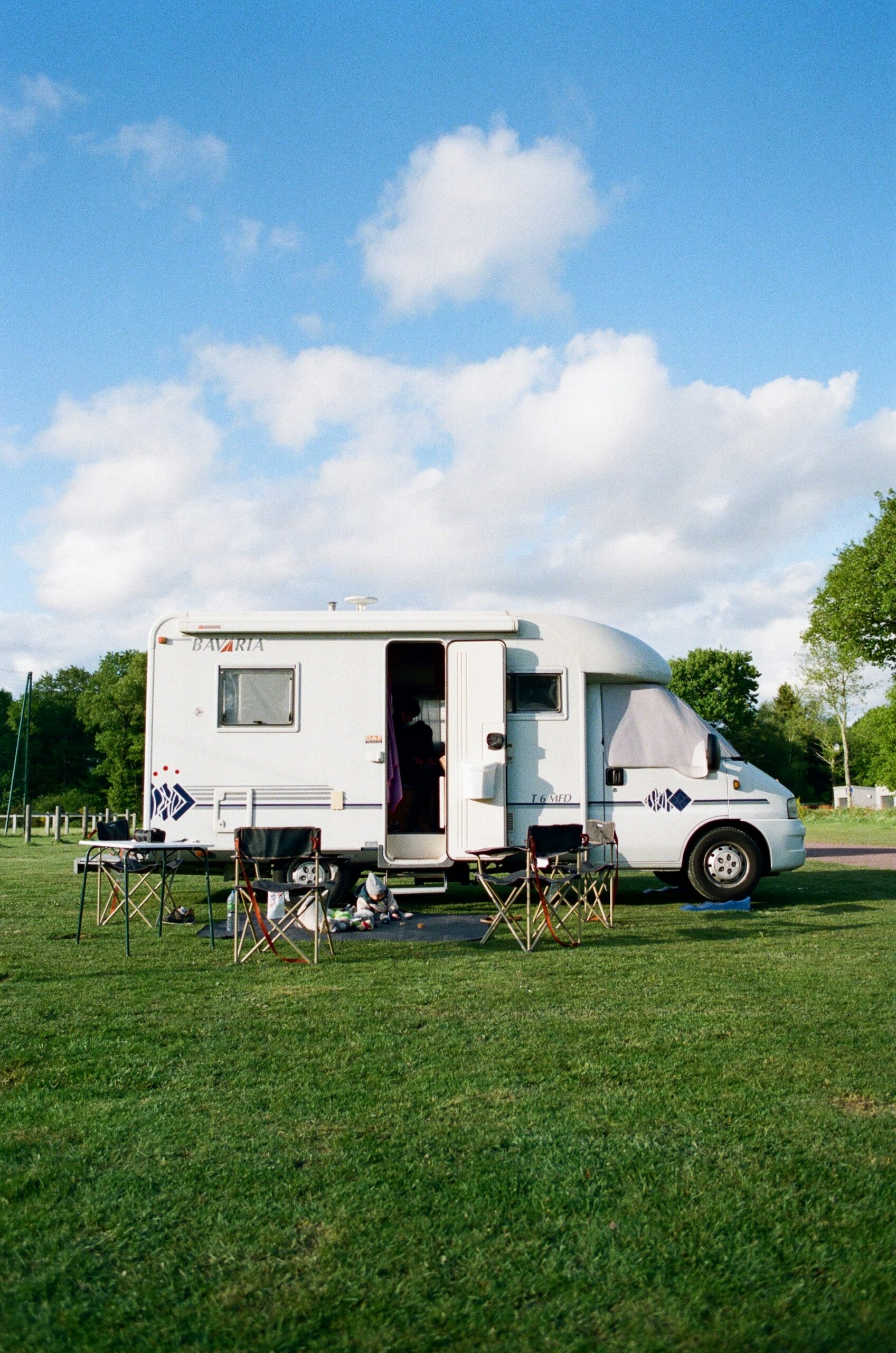 white campervan on green grass field under blue sky with clouds
