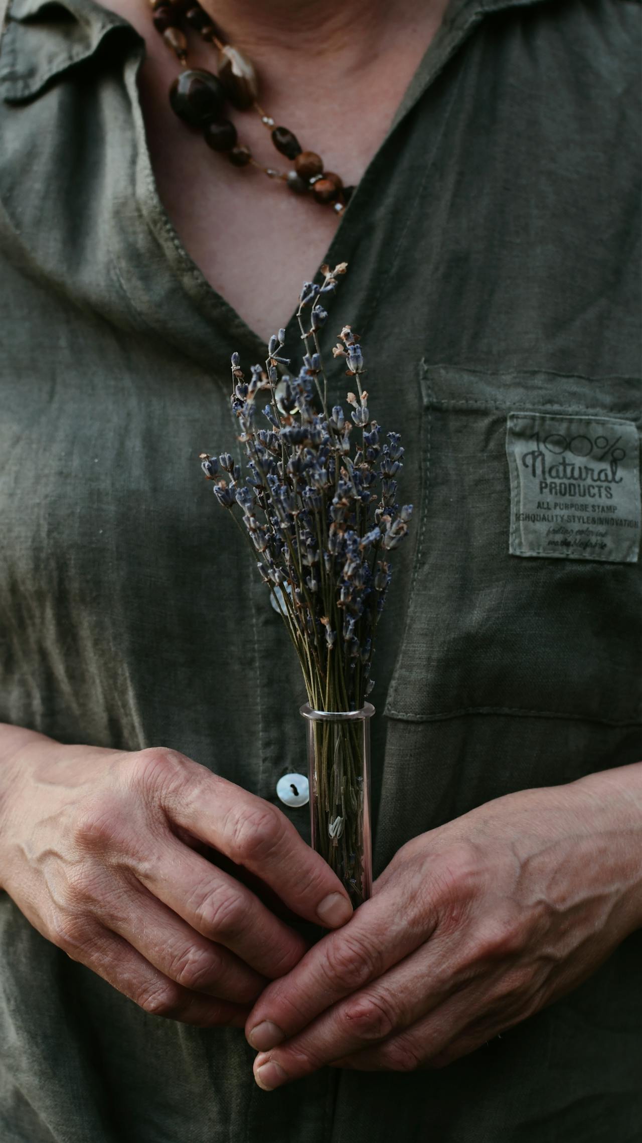 older woman with green shirt holding purple flowers older woman with green shirt holding purple flowers