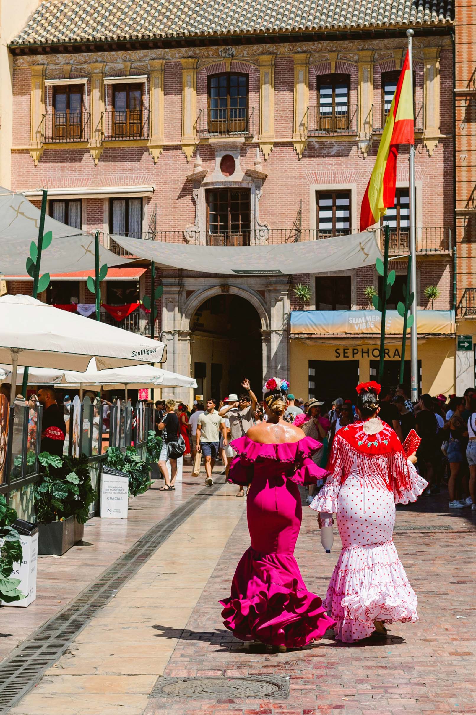 a couple of women in flamenco dresses walking down a street in Malaga
