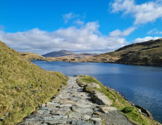 a stone path next to body of water photo